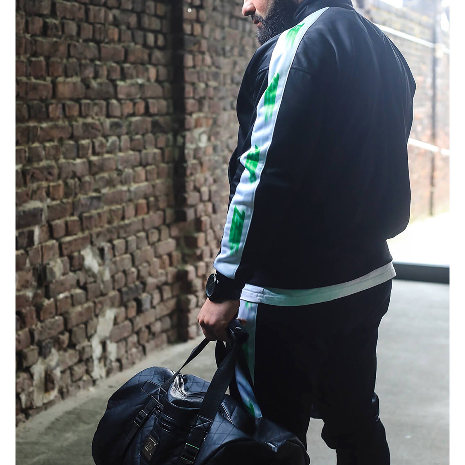 Zecplus Lifestyle Weekender Tasche Sporttasche schwarz gesteppt getragen von Mann vor Ziegelsteinmauer