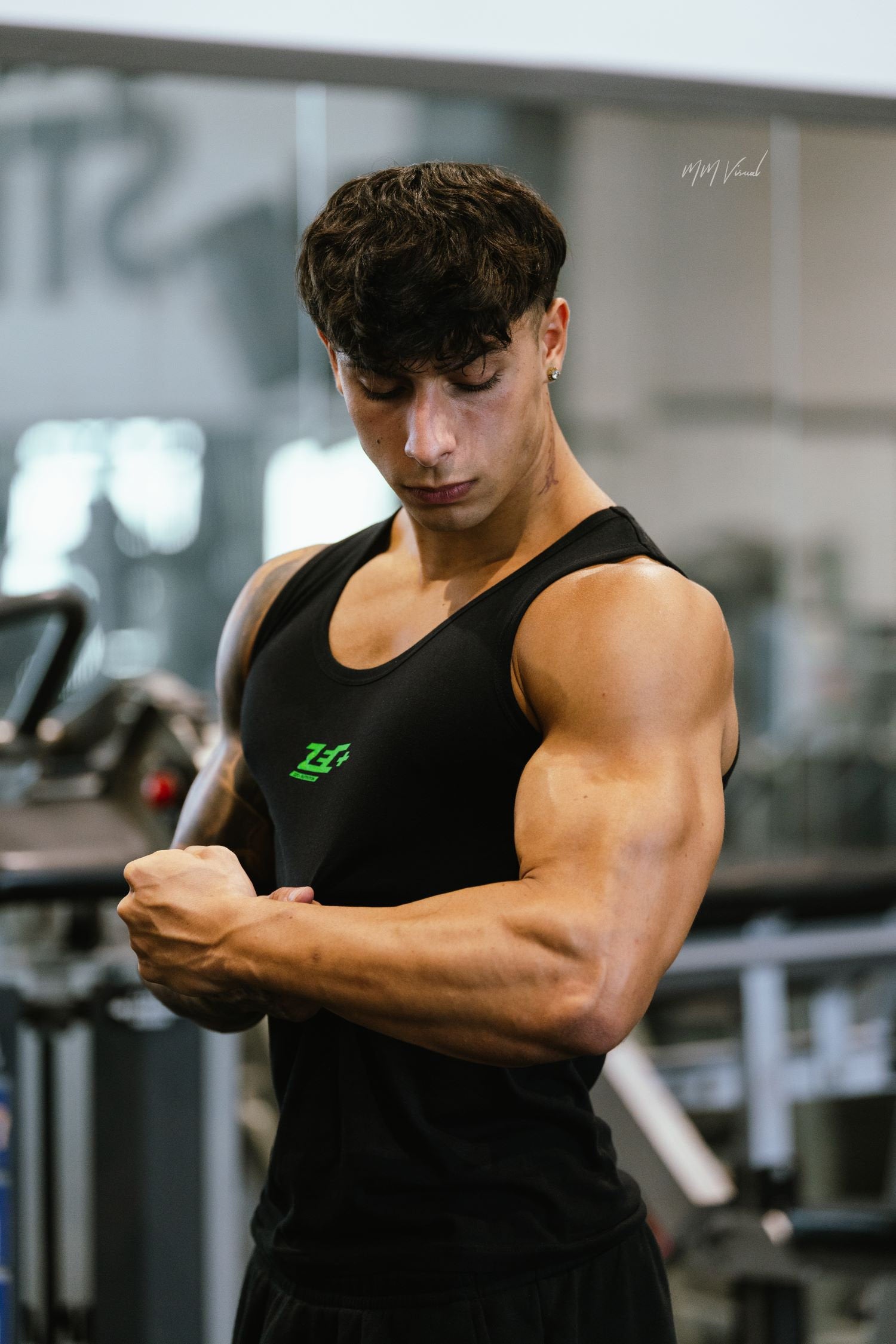 Athlet im schwarzen Zec+ Muskelshirt, Bizeps-Pose im Fitnessstudio